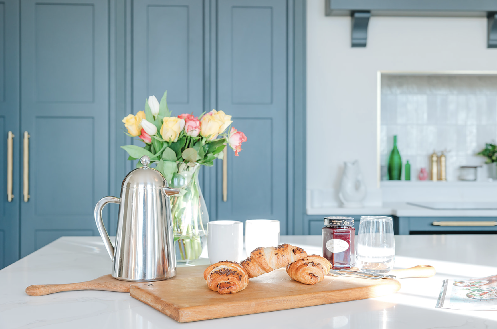 Marble-topped island in the Bicton Hall kitchen with teal inframe cabinetry and brass hardware behind