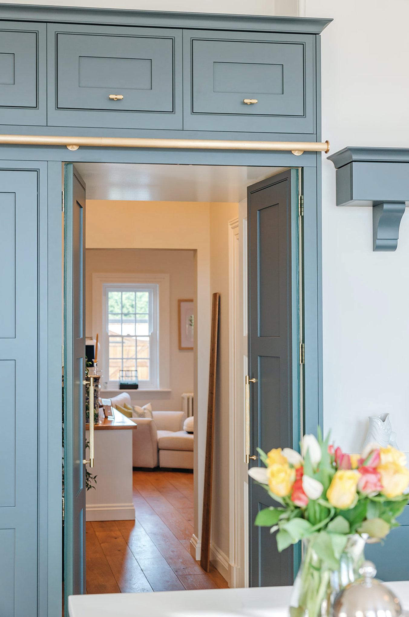 Utility and scullery with dark inframe cabinetry, marble floor, brass tap and butler sink, seen through to the hallway beyond