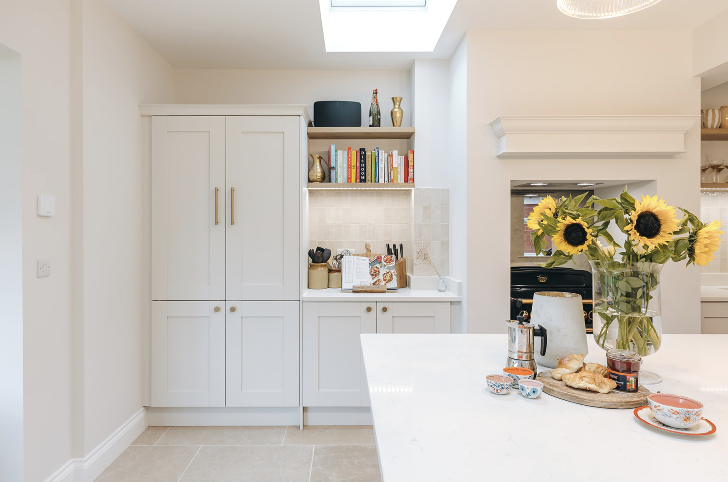 Cream kitchen with full-height larder cabinetry, rooflight and sunflowers on the island