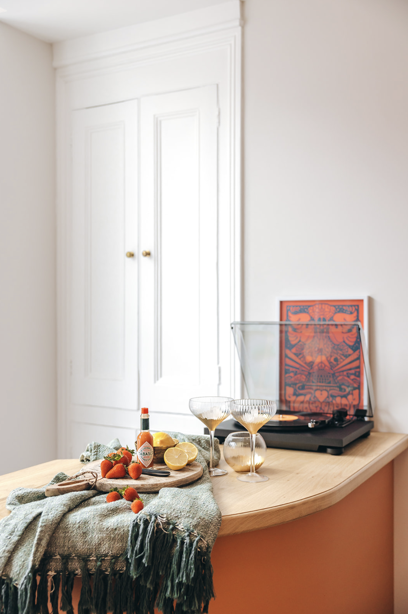 Curved oak bar top over terracotta joinery with a record player