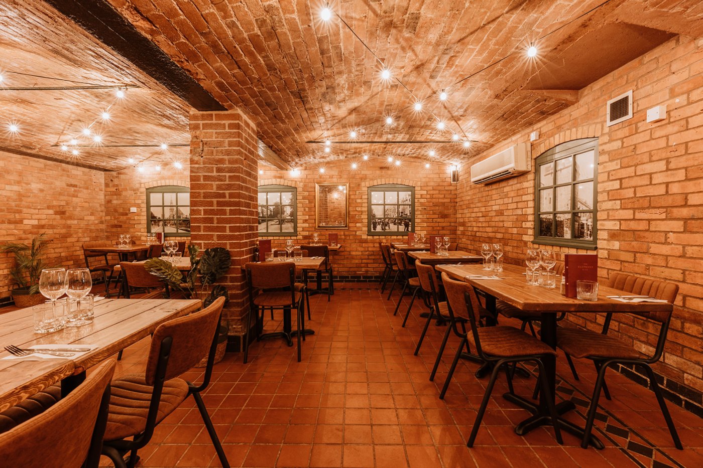 The Elephant Underground: vaulted brick dining room lit with festoon bulbs