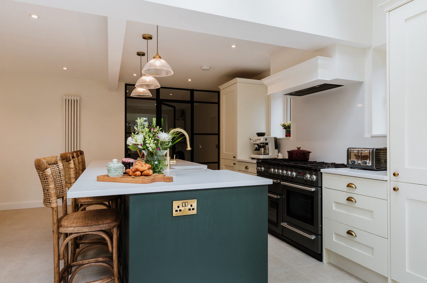 Green painted kitchen island beneath original beams
