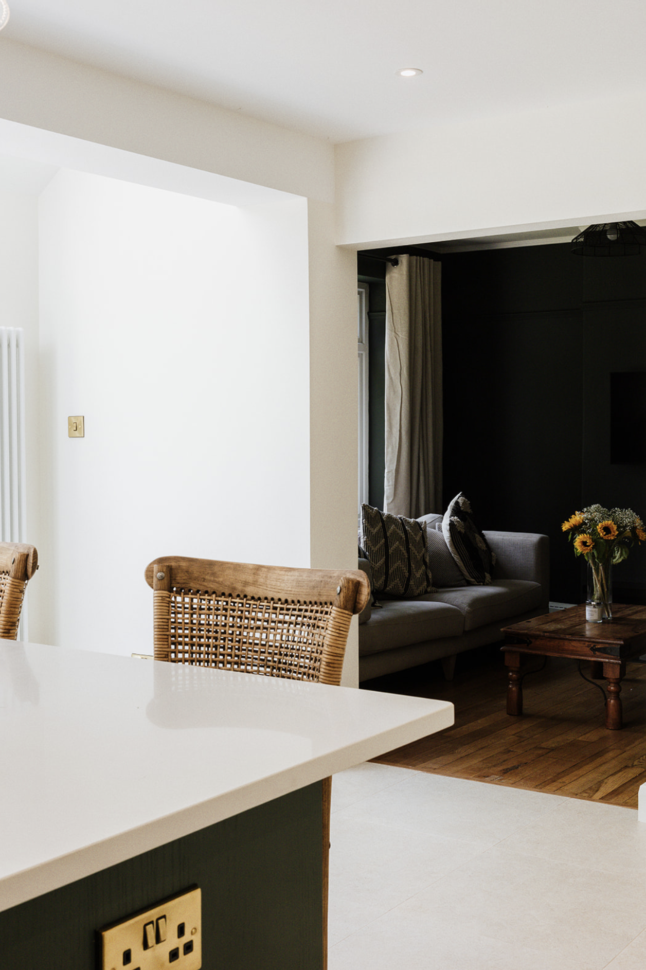 Cream shaker cabinetry with an espresso machine set into a niche beside a window, brass cup handles and a black range alongside