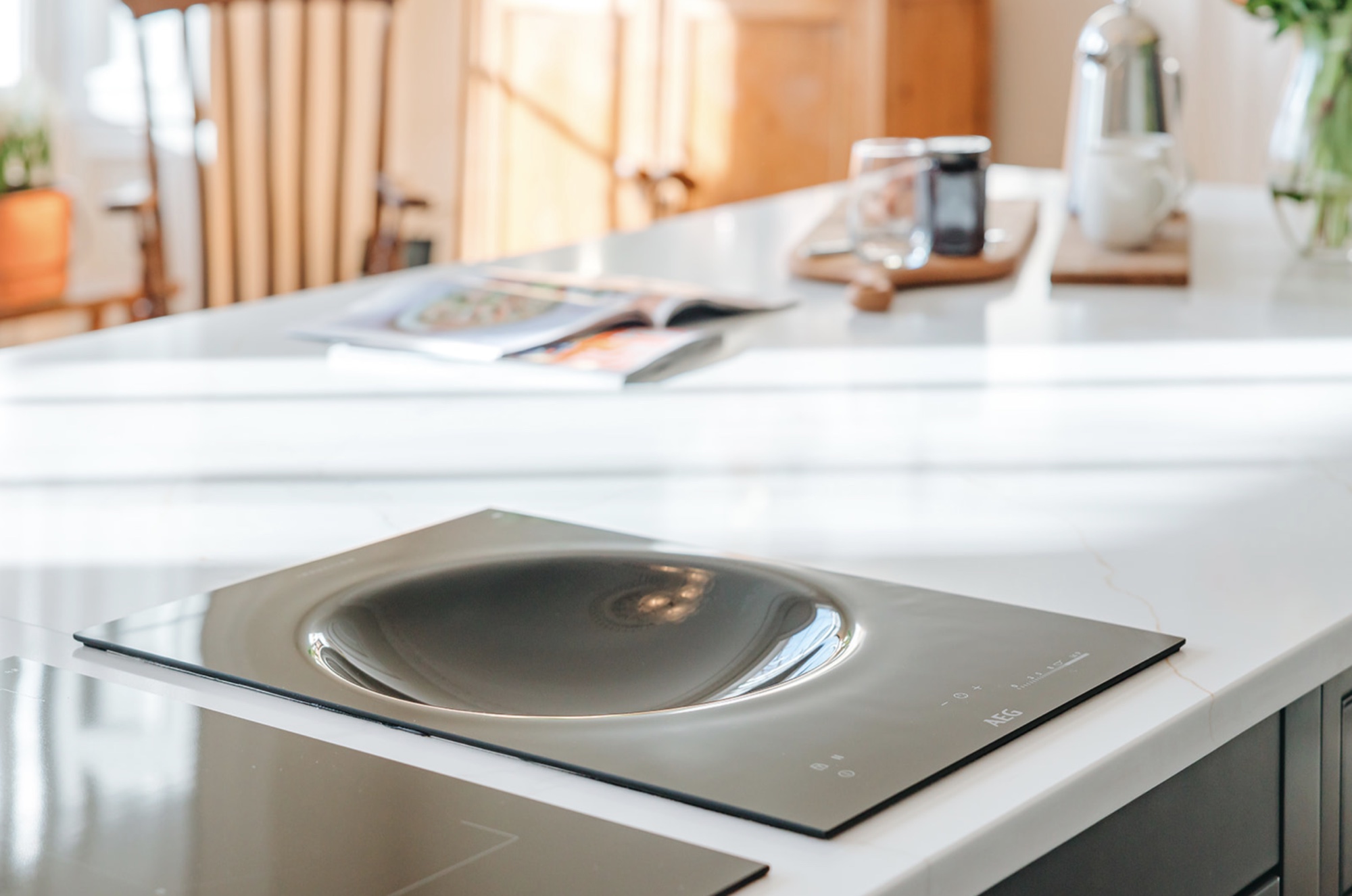 Black induction hob set flush into the white stone kitchen worktop