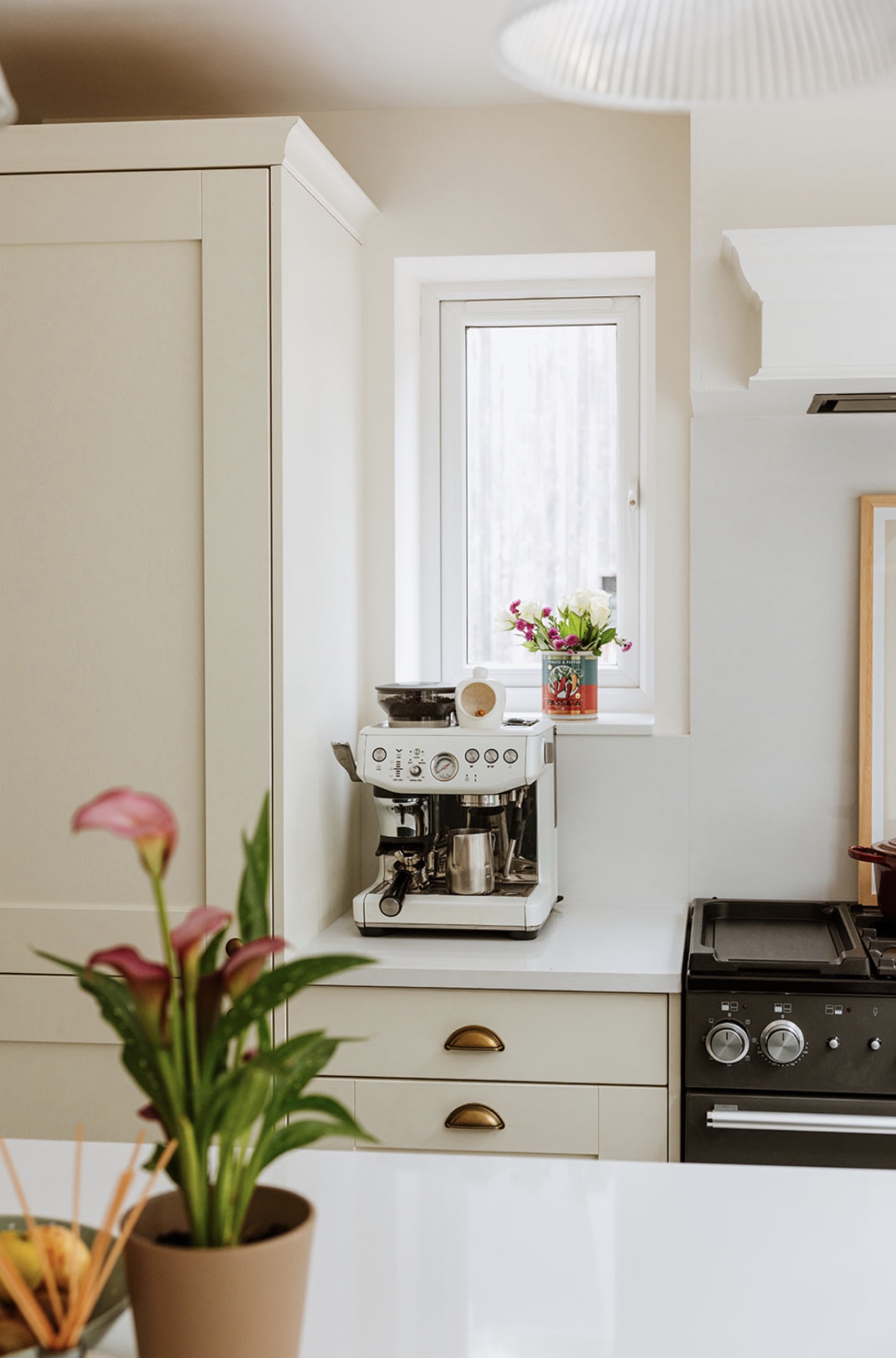 Coffee station tucked beneath a small window within the kitchen cabinetry