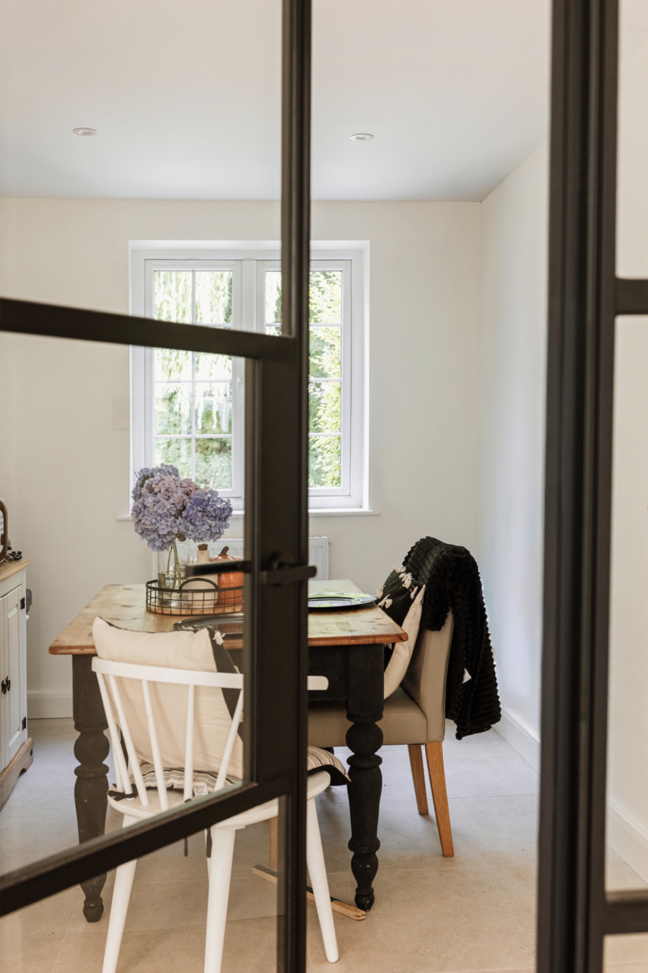 Family dining table seen through the black-framed glazed kitchen screen