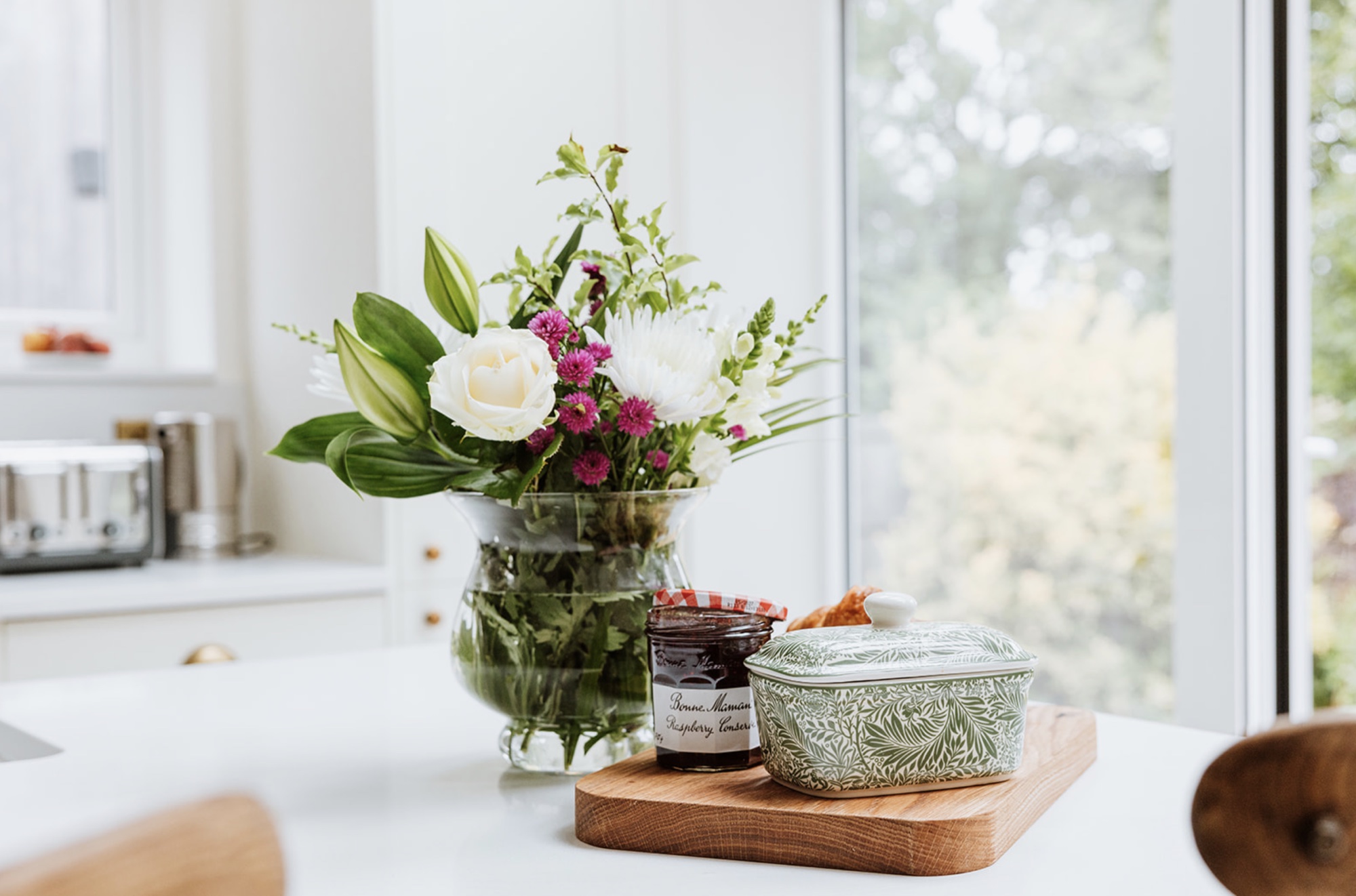 Flowers, preserves and patterned butter dish beside the garden window
