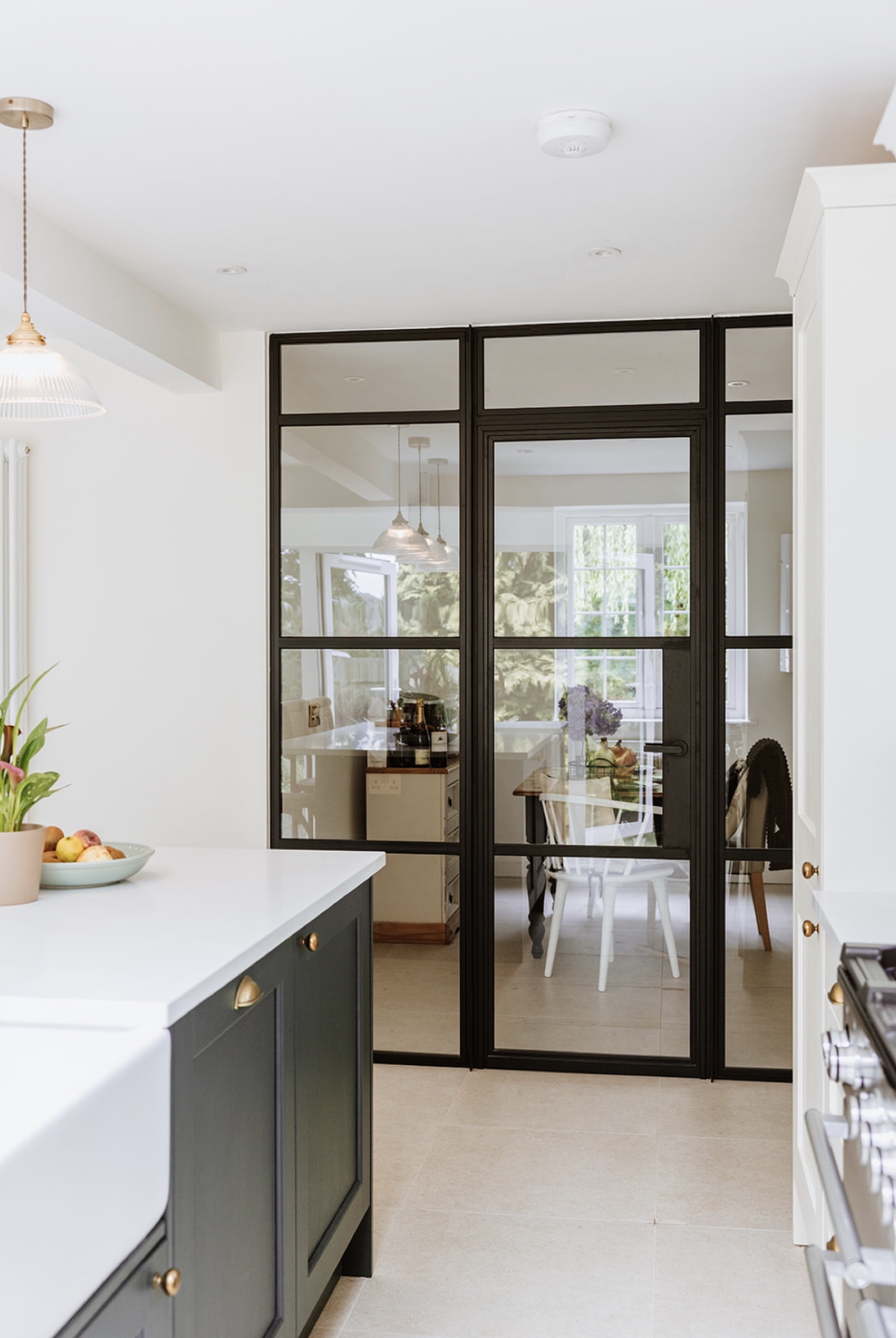 Black-framed glazed screen connecting the new kitchen with the dining room