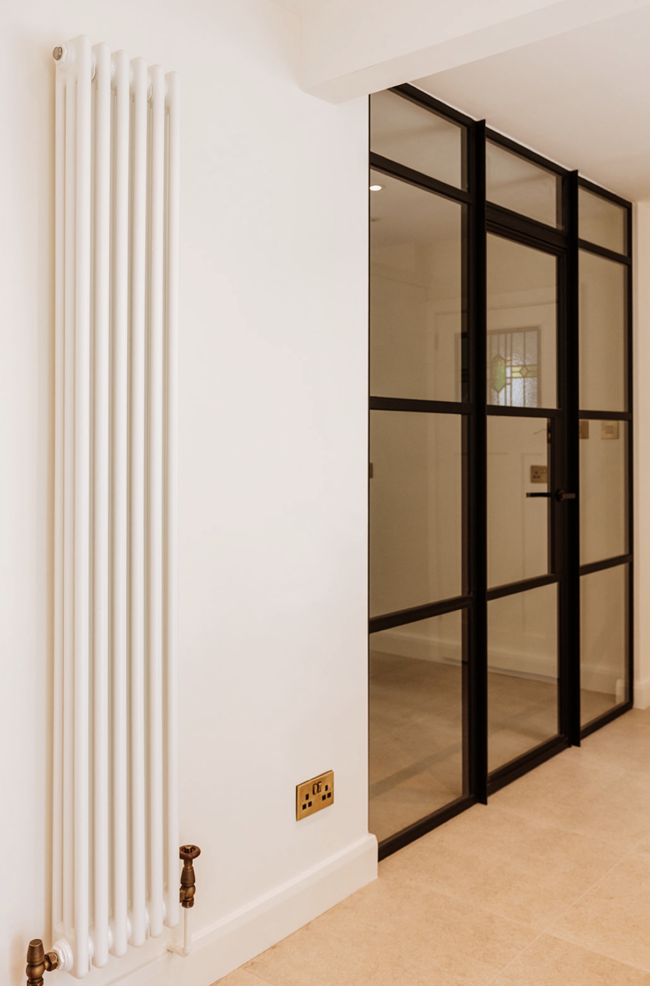 Black-framed glazed screen beside a traditional white column radiator