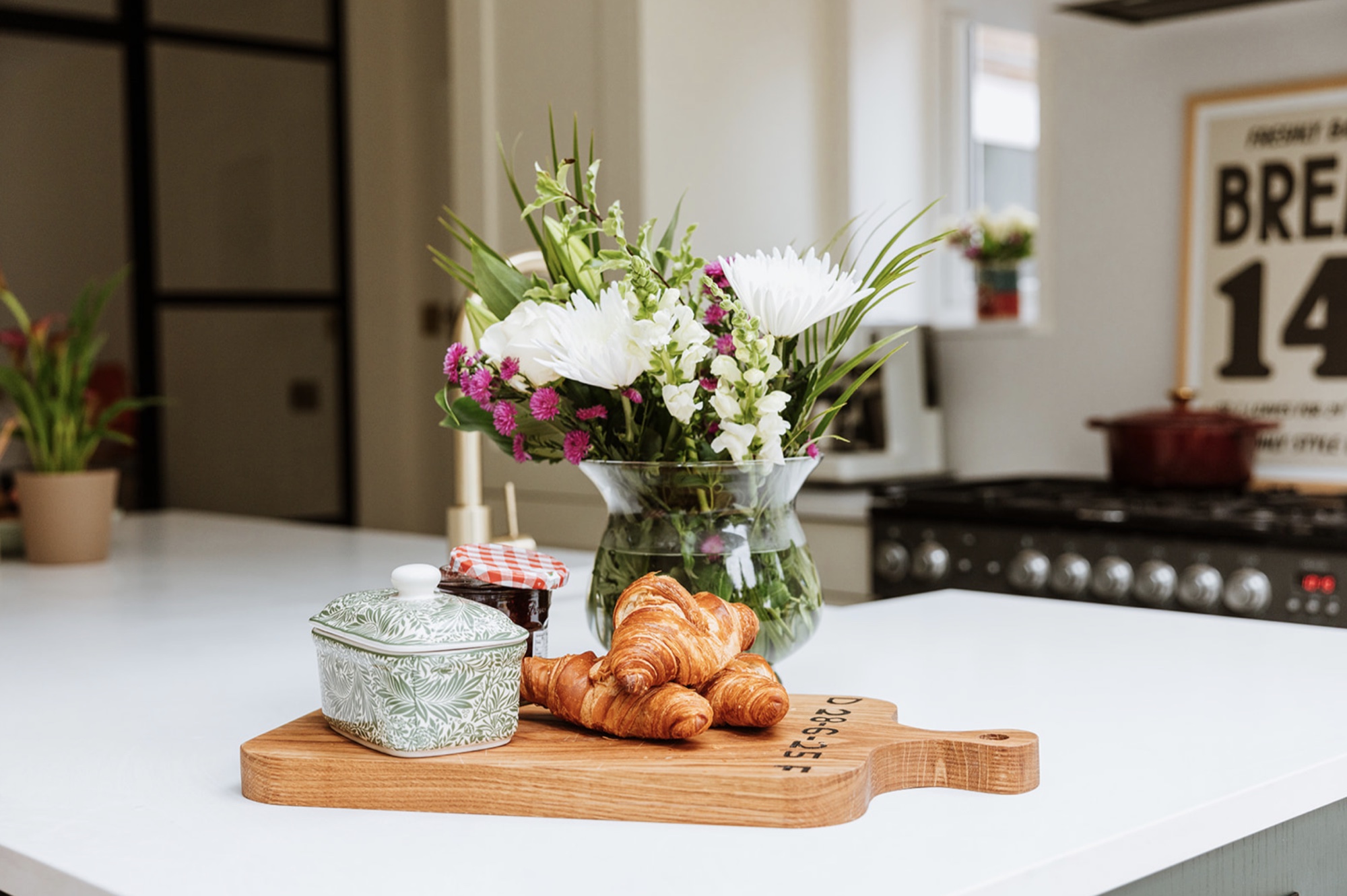 Croissants, flowers and preserves arranged on the white kitchen island