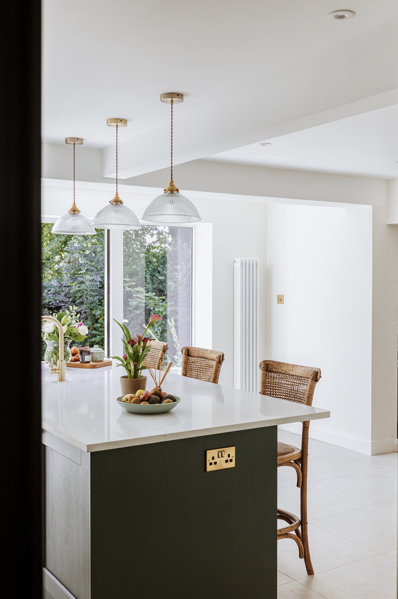 Fairholm's green kitchen island beneath three ribbed glass pendant lights