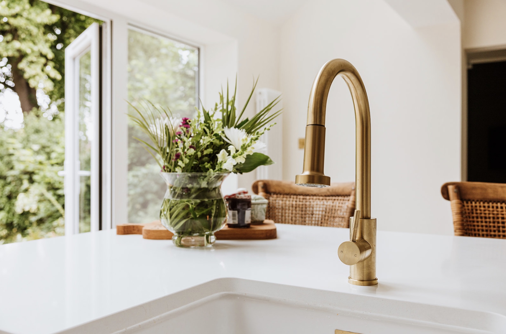 Brushed brass kitchen tap with flowers and the garden beyond