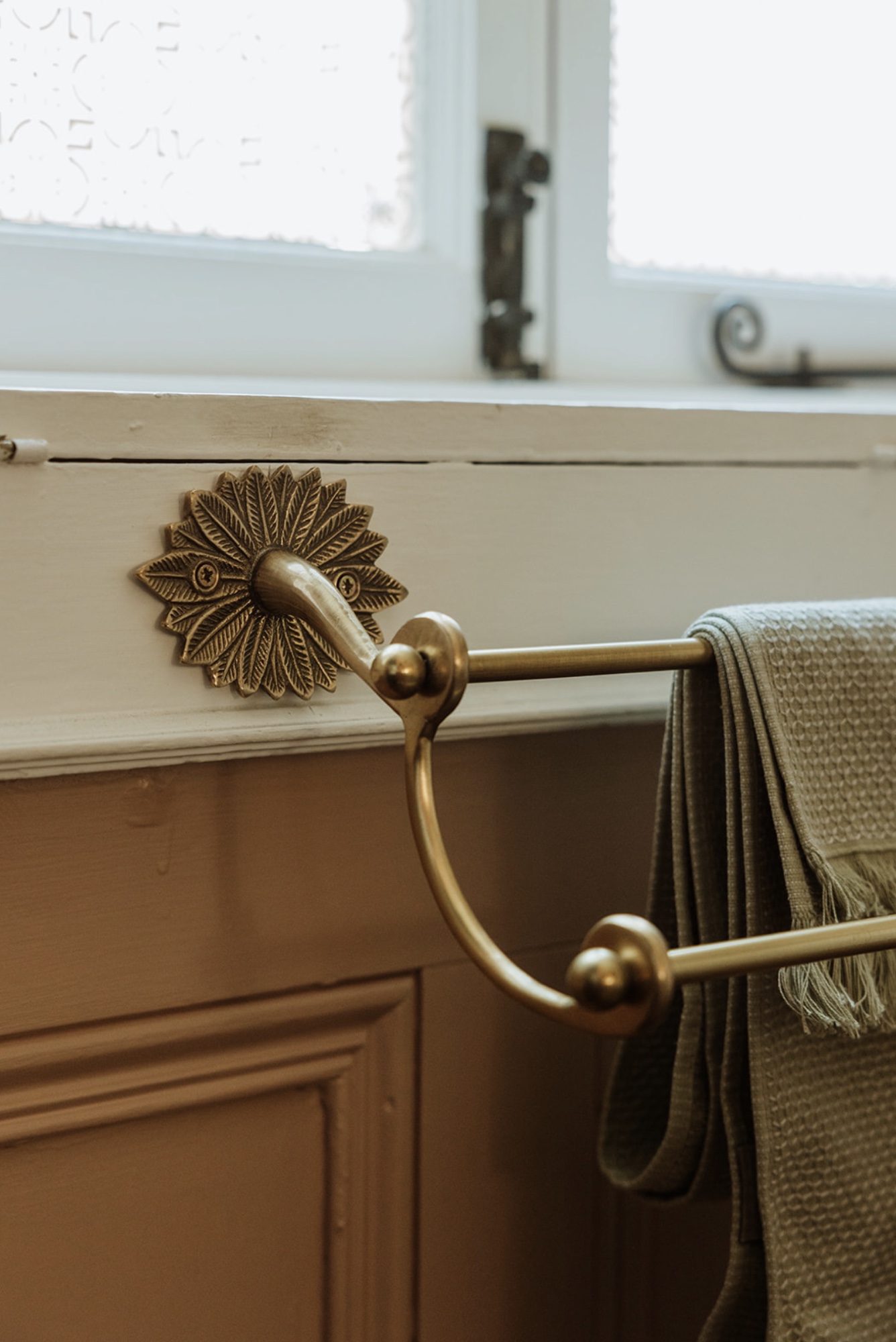 Decorative brass towel rail detail beneath an original window