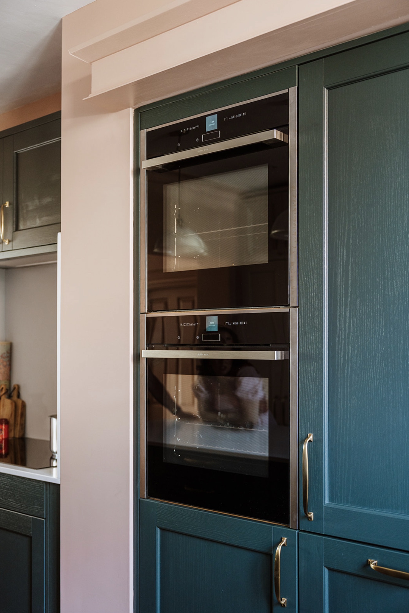 Double ovens integrated into deep green kitchen cabinetry