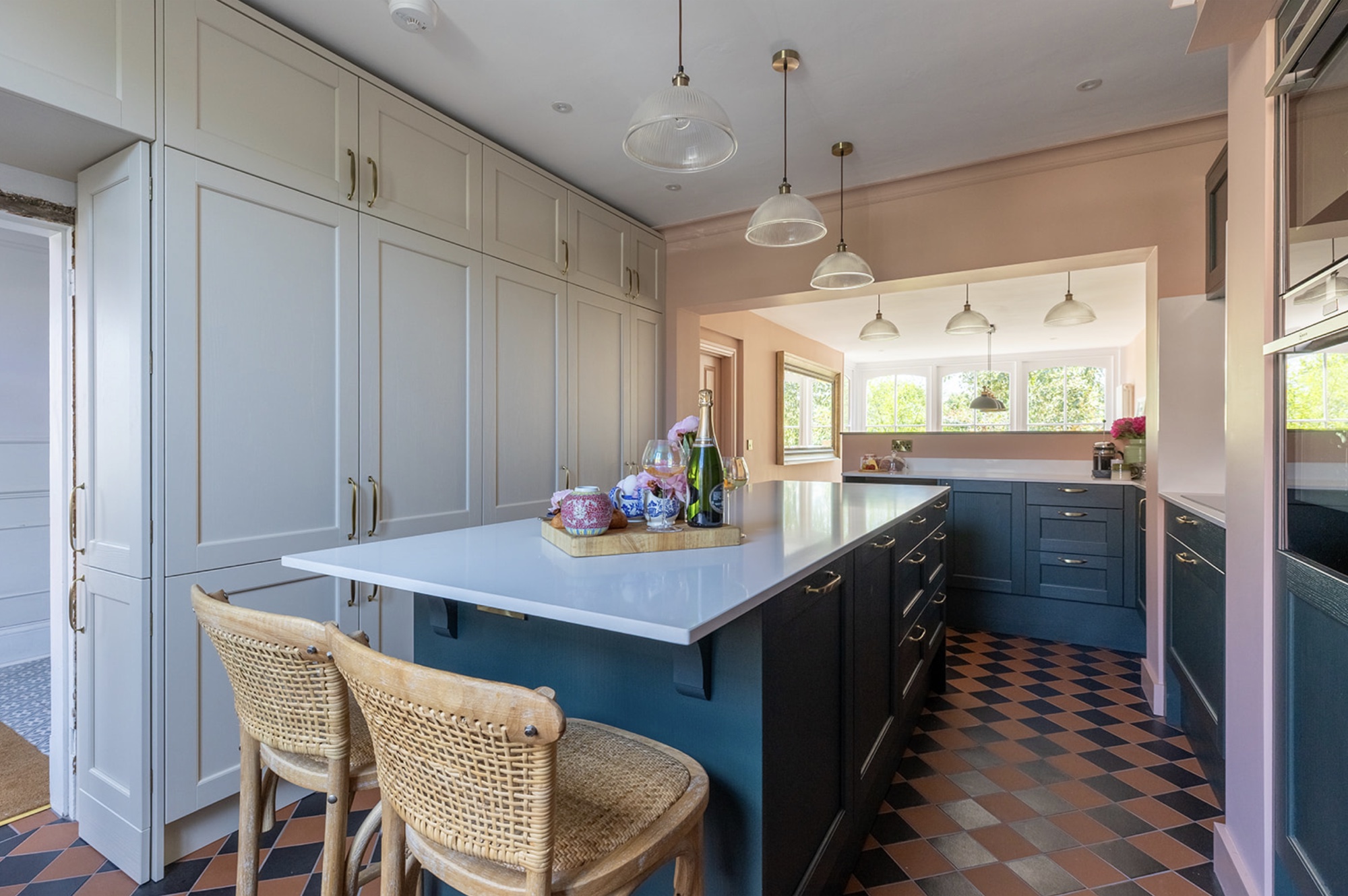 Oak Street's completed kitchen with a deep green island, linen cabinetry and checkerboard floor