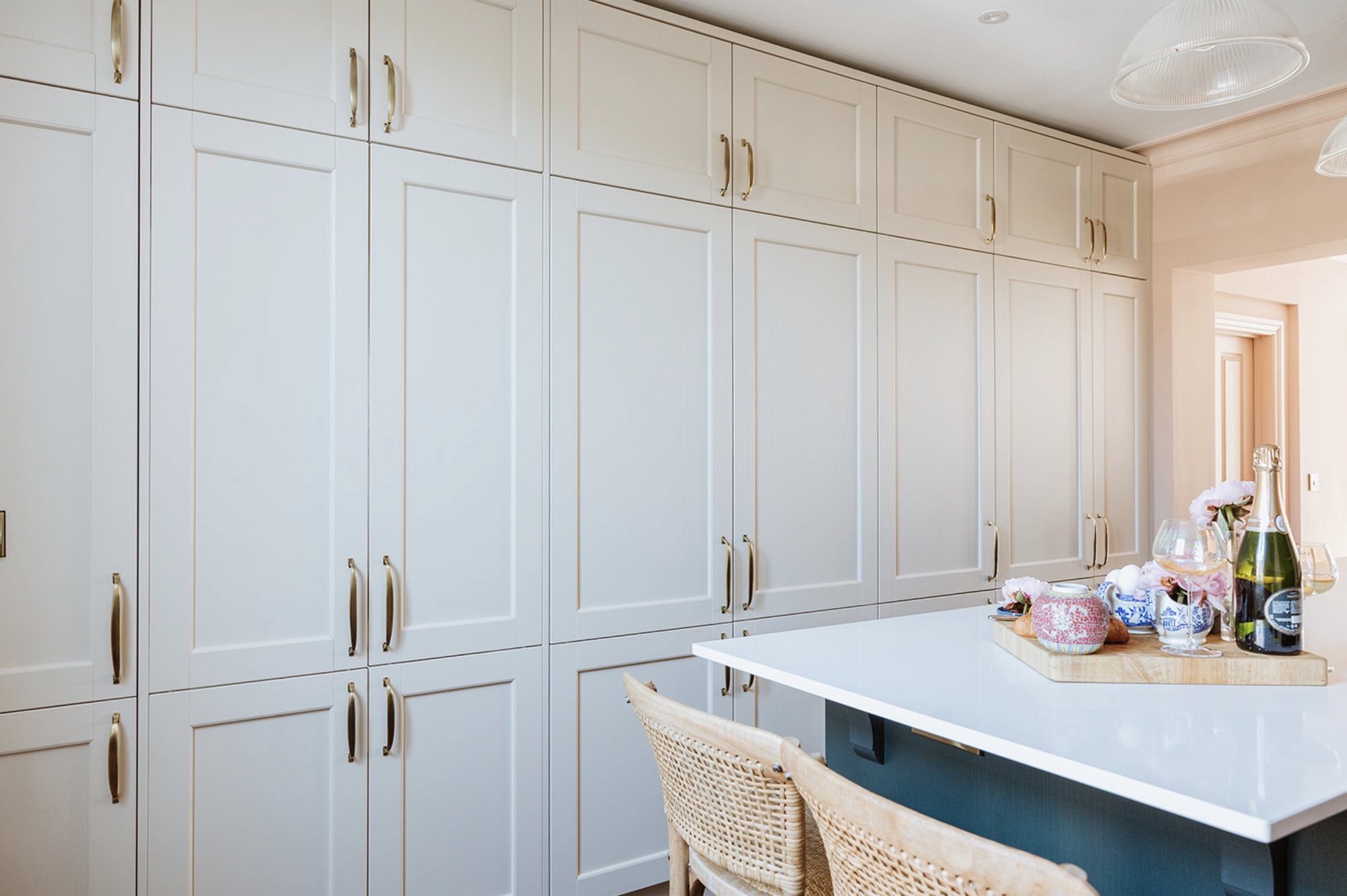 Full-height linen-coloured pantry cupboards beside the kitchen island