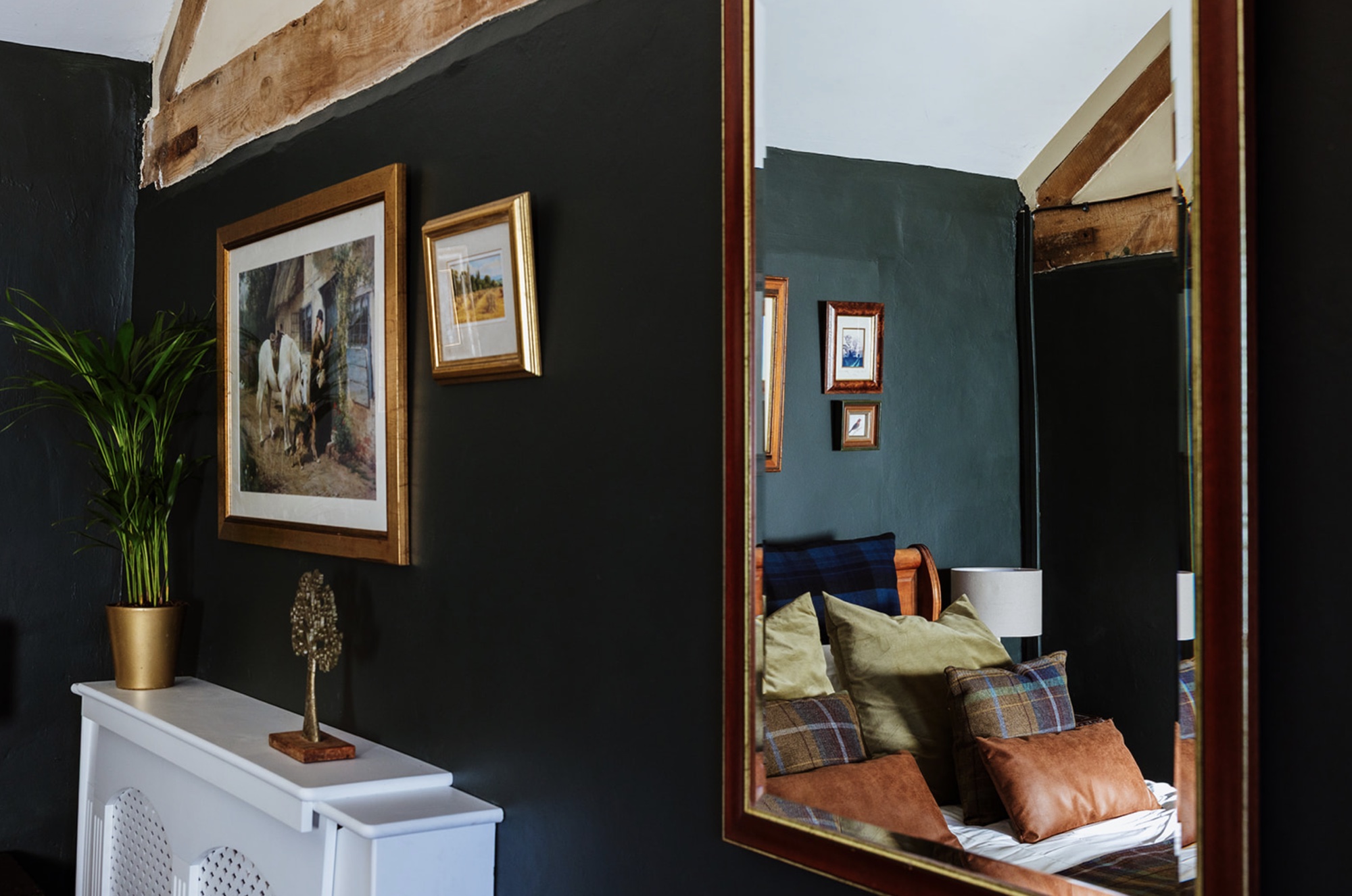 Large framed mirror reflecting the Pool House bed and exposed timber beams