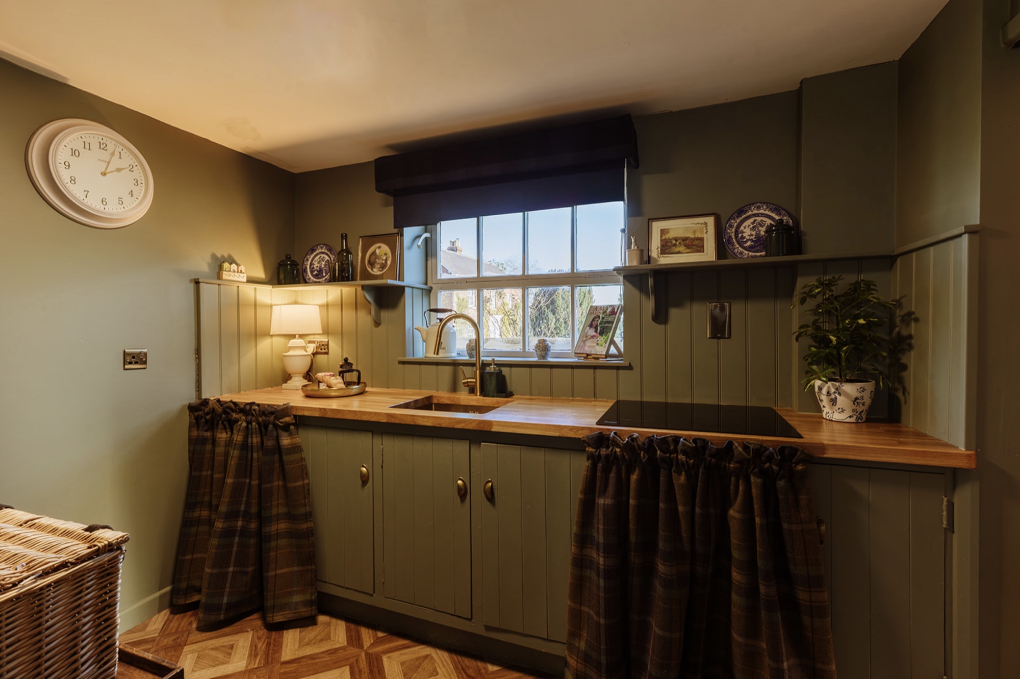 The completed Pool House kitchenette with green joinery, oak worktop and a central window