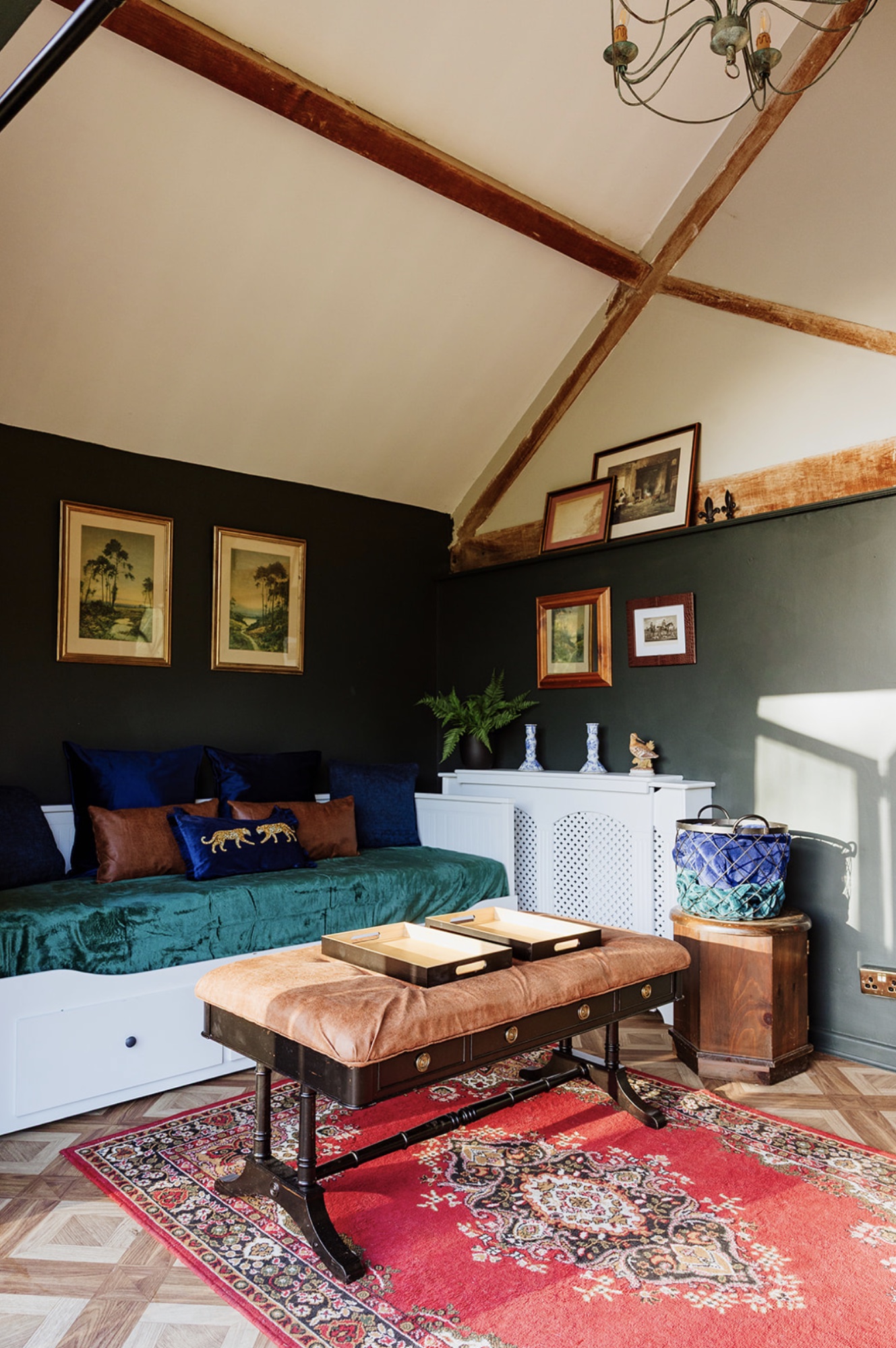 The Pool House lounge with a green velvet daybed, antique bench and exposed timber beams